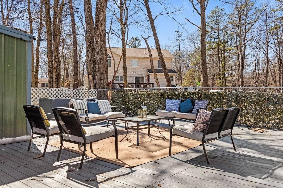 Sunny Relaxation Area: Bask in the sun on plush lounge chairs with a refreshing drink in hand. The patio is adorned with colorful cushions and potted plants for a cheerful ambiance.